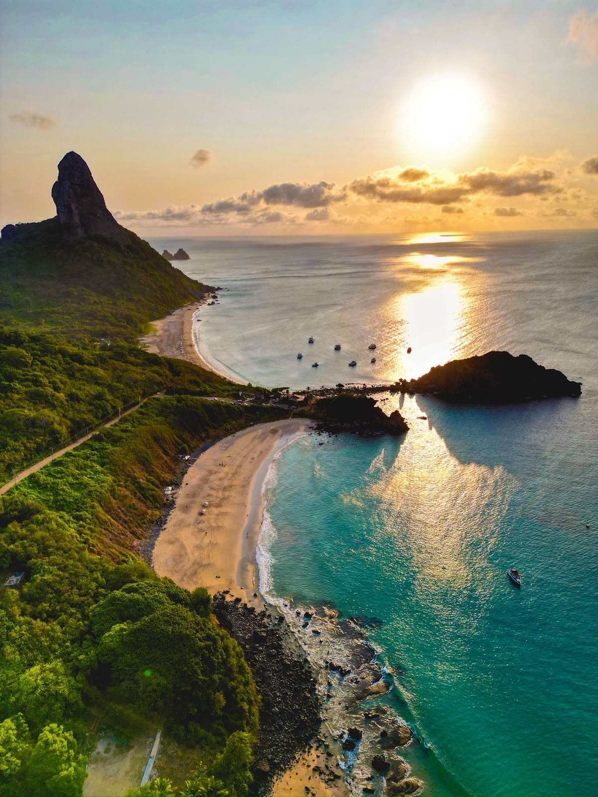 Vista aérea do Morro do Pico e das praias de Fernando de Noronha ao pôr do sol